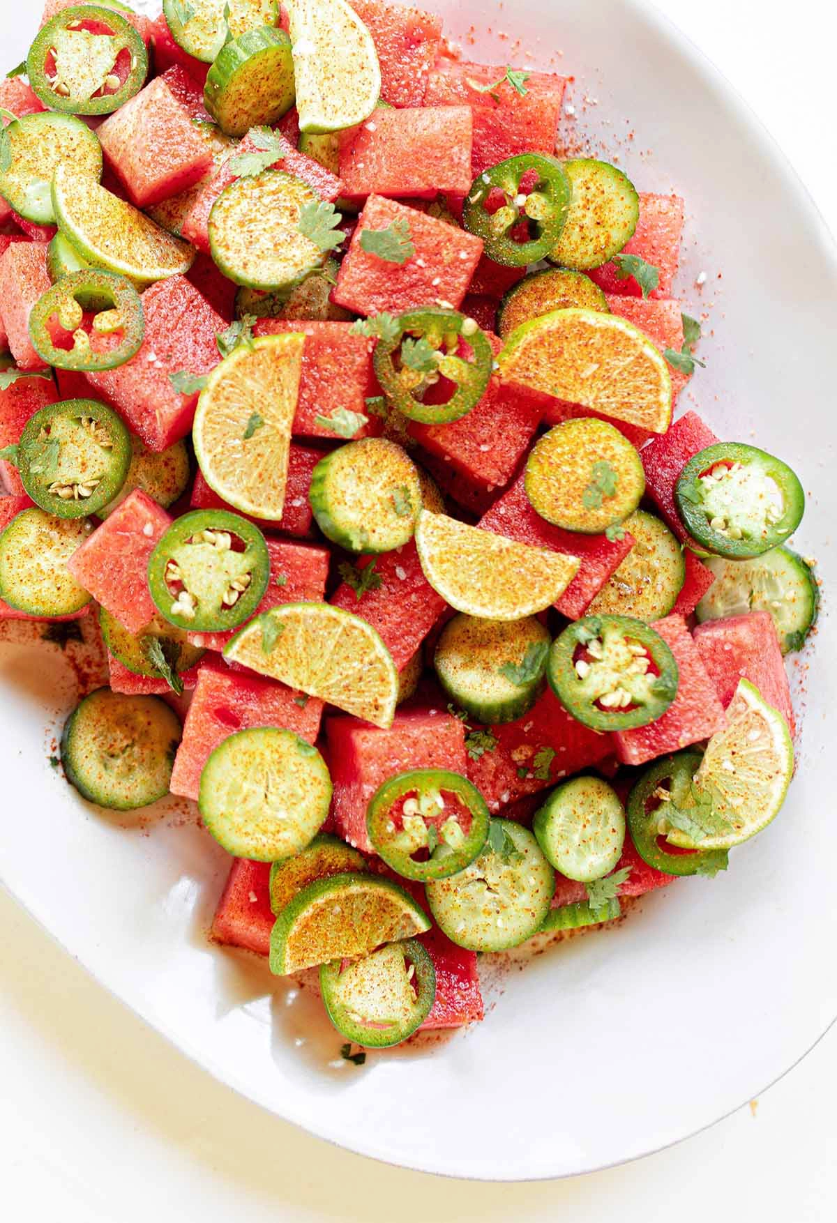 chili lime watermelon cucumber salad on a large plate on a white background